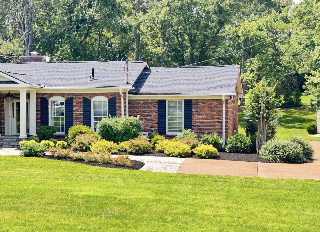 Brick ranch home with freshly trimmed shrubs, layered plantings, and a clean lawn
