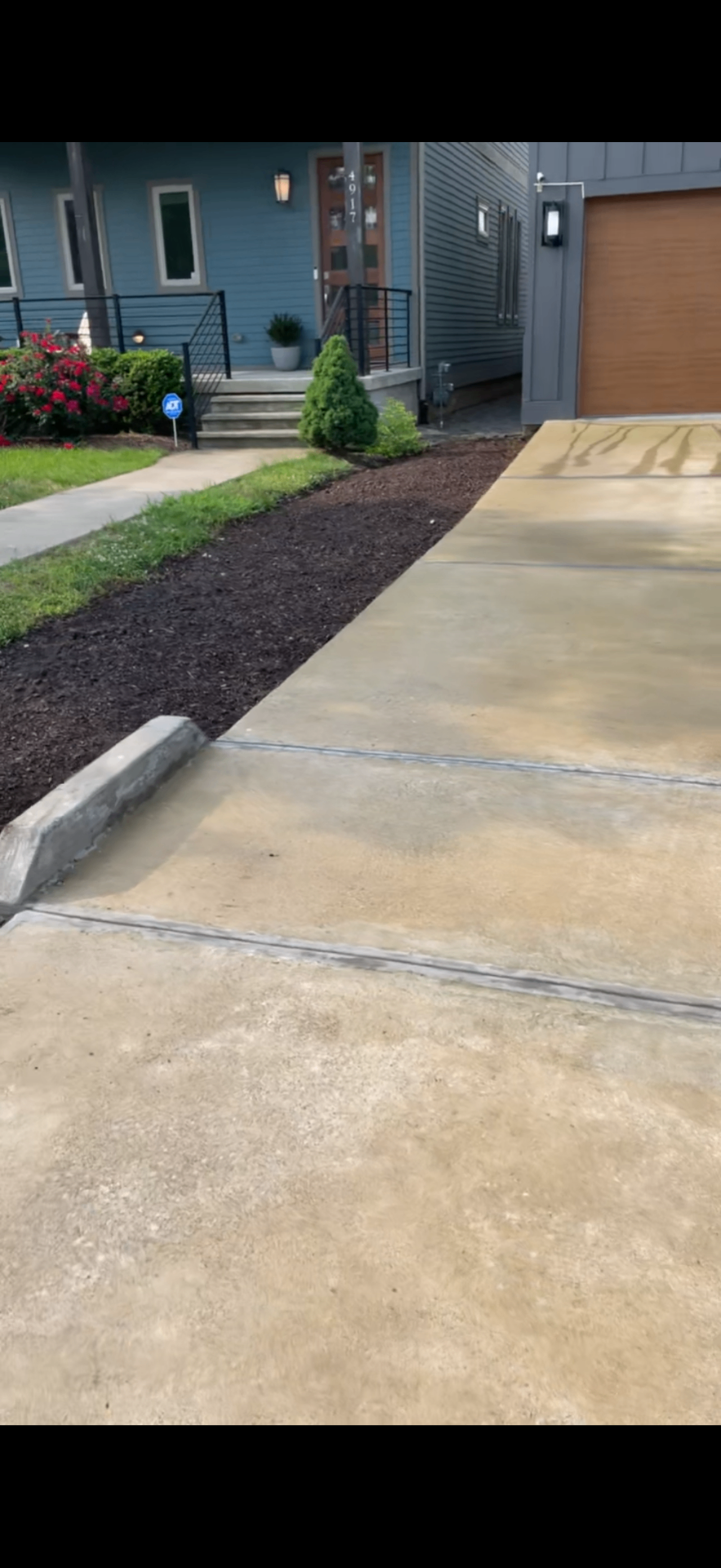 Fresh mulch bed edged neatly along a driveway in front of a modern home