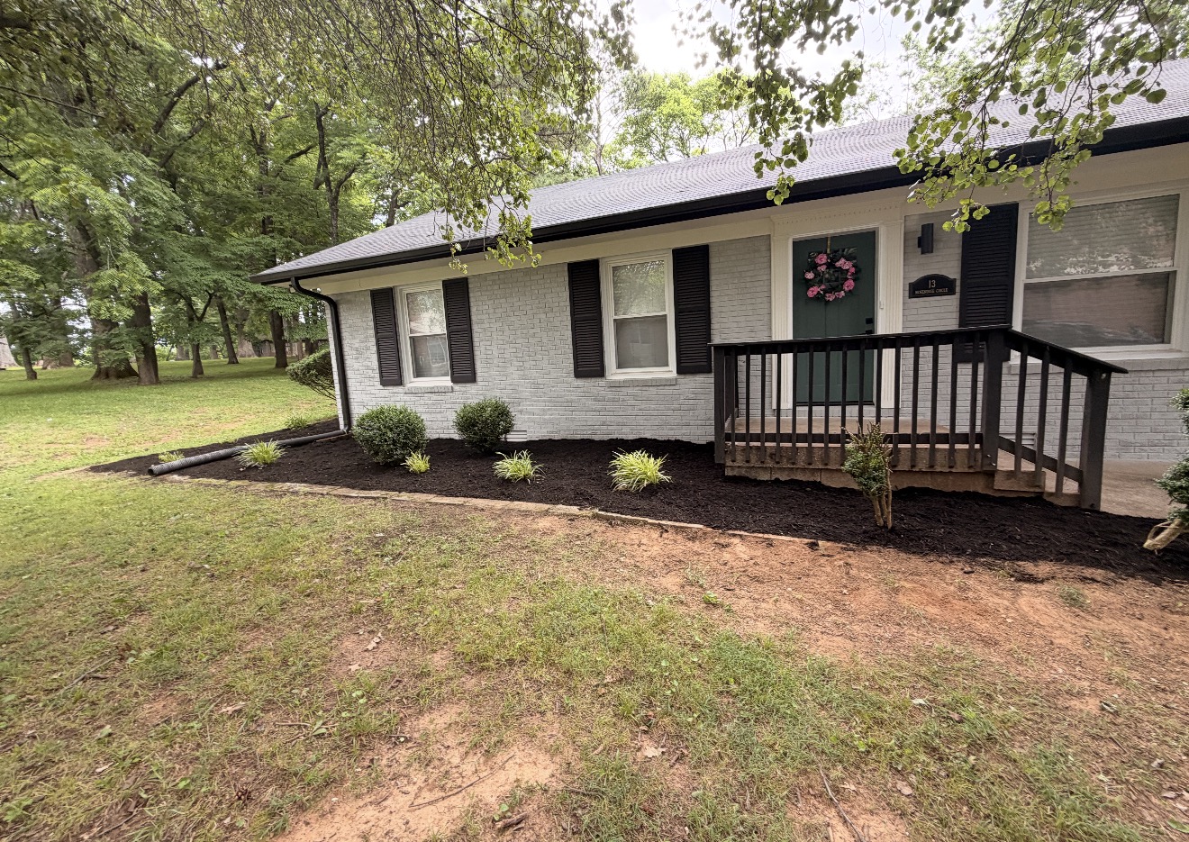 White brick home with fresh mulch beds and new plantings along the foundation